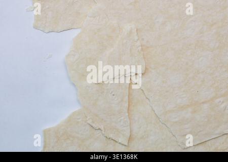 Pezzi di matzah danneggiati e rotti su sfondo bianco, vista dall'alto; fogli di impasto arrotolato su sfondo bianco. Pezzi di lavash, vista dall'alto, Chiudi Foto Stock