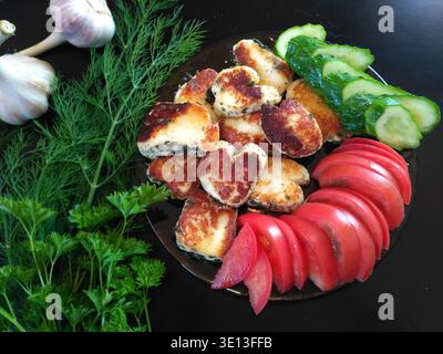 Pezzi di halloumi fritti su un piatto e pomodori e cetriolo Foto Stock