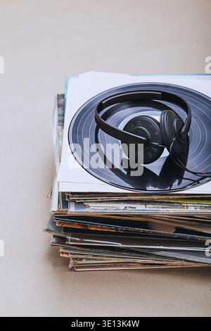 Stack di molti dischi e cuffie in vinile nero sulla parte superiore dello stack. Persone since, momenti reali, situazioni autentiche Foto Stock