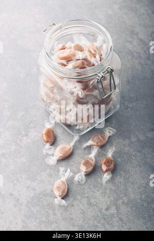 Vaso riempito con caramello caramelle lattiginoso sul tavolo Foto Stock