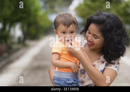 Ritratto di felice madre asiatica e bambino multietnico figlio che si lega insieme all'aperto Foto Stock