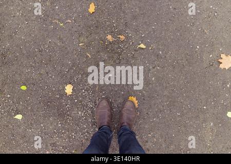 Tettuccio di tiro dell'uomo in piedi sul terreno concreto e le scarpe marrone Foto Stock