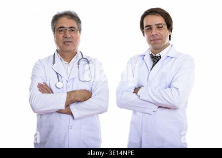 Studio shot di giovani e senior uomo persiano medico con le braccia incrociate Foto Stock