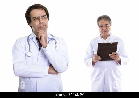 Giovane uomo persiano medico pensando con senior uomo persiano medico lettura sulla clipboard Foto Stock