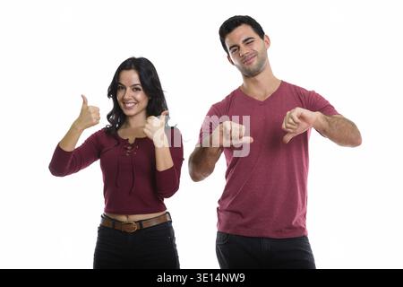 Studio shot di giovani felice coppia sorridente con la donna dando Thumbs up e uomo dando il pollice verso il basso Foto Stock