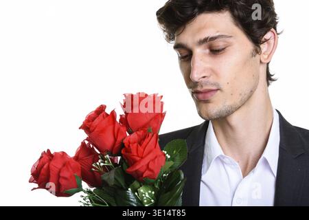 Primo piano di un giovane bel uomo d'affari che tiene e guardando rose rosse Foto Stock