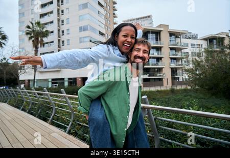 Coppia interrazziale che sorride alla macchina fotografica all'aperto Foto Stock