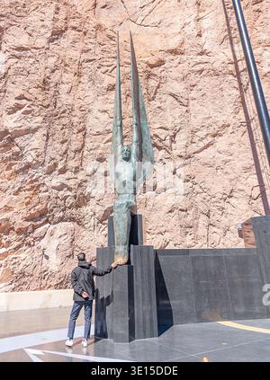6 marzo 2026, Boulder City, Nevada, USA: Un turista tocca i piedi dalle figure alate della statua della Repubblica presso la diga di Hoover a Boulder City, Nevada Foto Stock