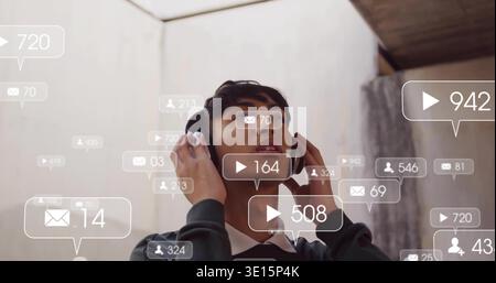 Con le cuffie in mano, uomo che guarda sotto il lucernario nell'atrio con avvisi fluttuanti, maglione scuro Foto Stock
