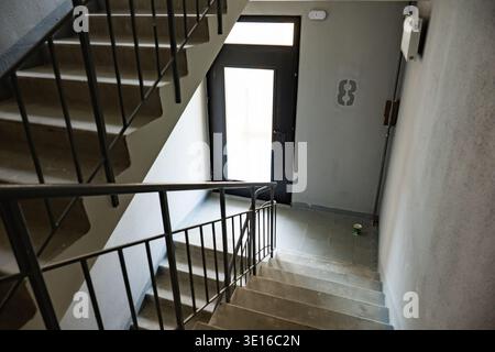 Scala in cemento che conduce ad una porta d'ingresso in un corridoio di un edificio Foto Stock