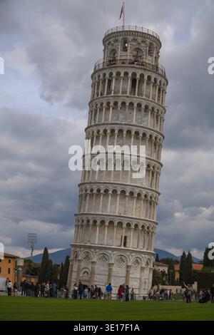 Torre pendente di Pisa, Torre pendente di Pisa. I turisti si radunano su un prato verde sotto il campanile medievale di Pisa, sotto le nuvole. Foto Stock