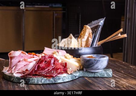 Un delizioso tagliere di salumi con un assortimento di prosciutto stagionato e affettati sottili. Presentato su un tavolo rustico, perfetto per piatti gourmet Foto Stock