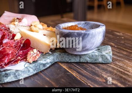 Un delizioso tagliere di salumi con prosciutto stagionato, formaggi assortiti e noci miste. La tavola è disposta ad arte, perfetta per uno stile gastronomico Foto Stock