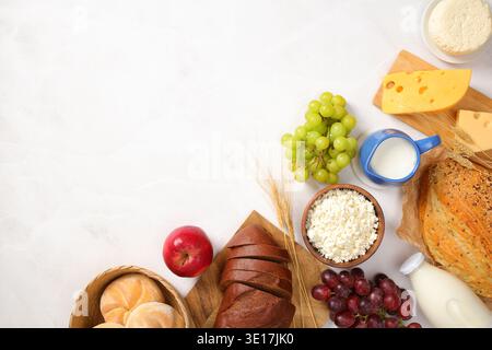Una selezione splendidamente organizzata di prodotti caseari Shavuot con formaggio, latte e formaggio fresco, circondati da pane fresco, uva verde e rossa, ap Foto Stock