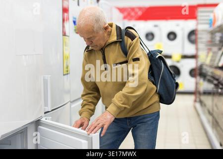 senor uomo pensionato acquistare frigorifero in showroom di elettrodomestici negozio Foto Stock