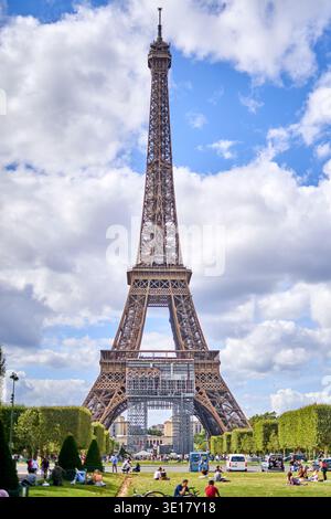 La Torre Eiffel si erge maestosamente contro un cielo blu brillante punteggiato da soffici nuvole bianche, vista dal parco Champ de Mars di Parigi... Foto Stock