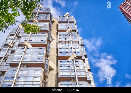 Una suggestiva vista ad angolo basso di un alto e moderno edificio residenziale o di uffici caratterizzato da un design architettonico contemporaneo con tende di vetro... Foto Stock