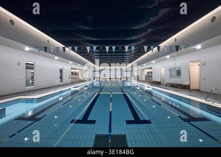 Piscina coperta con luce brillante e acqua blu riflettente. Foto Stock