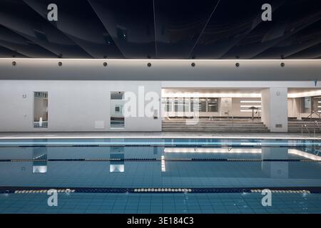 Piscina coperta con luce brillante e acqua blu riflettente. Foto Stock