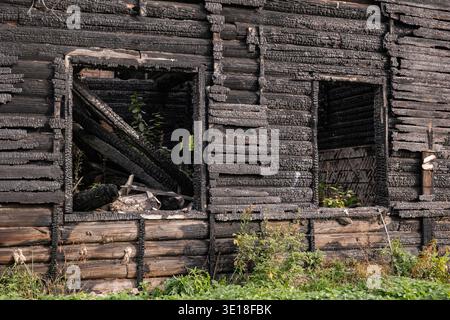Facciata di case in legno carbonizzato dopo il fuoco, dimostrando devastazione e distruzione Foto Stock