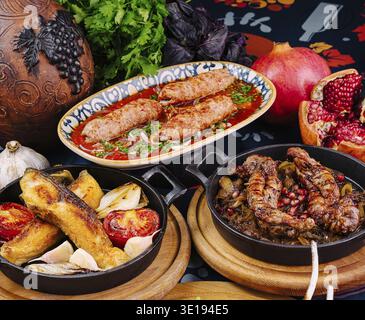 Deliziosa cucina tradizionale georgiana con kebab lula, pesce alla griglia, stufato di carne e verdure fresche servite sul tavolo Foto Stock