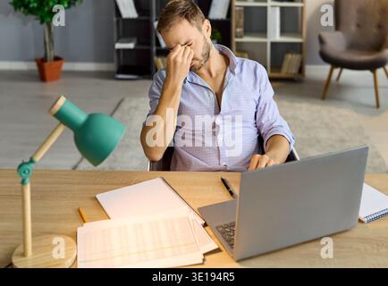 Ha sottolineato un uomo con mal di testa, che ha esaminato i documenti per la revisione in mezzo alla crisi finanziaria sul posto di lavoro Foto Stock