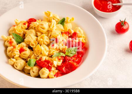 Pasta ripiena italiana. Sacсhettini pasta in un piatto con salsa di pomodoro. Foto Stock