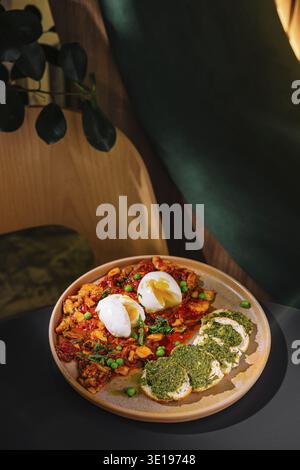 Moderno caffè che serve un pasto delizioso e salutare di shakshuka con uova in camicia e bruschetta al pesto Foto Stock