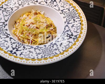 Gli spaghetti alla carbonara sono serviti su un piatto dal design elegante, che propone cucina italiana Foto Stock