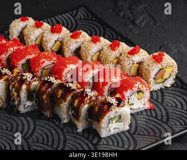 Lussuoso assortimento di sushi roll disposti artisticamente su un elegante piatto nero con sfondo testurizzato Foto Stock