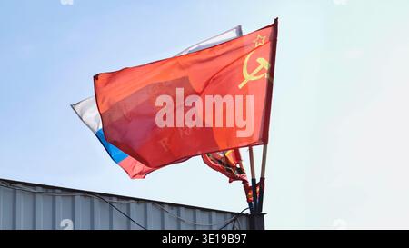 Bandiere sovietiche e russe che sventolano nel vento su una recinzione metallica Foto Stock