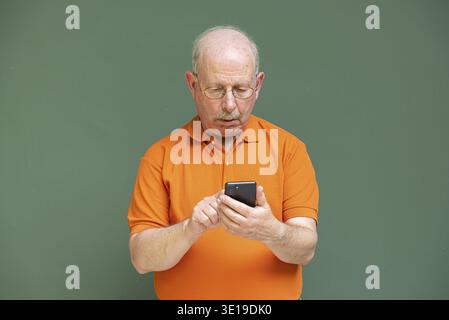 Ritratto di uomo anziano dai capelli grigi con baffi che indossano gli occhiali e che usano il telefono cellulare Foto Stock