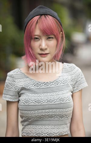 Ritratto di giovane bella donna asiatica con i capelli rosa per le strade all'aperto Foto Stock