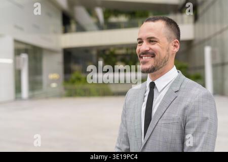 Ritratto di un uomo d'affari ispanico con la barba calva che indossa un abito nelle strade della città all'aperto Foto Stock