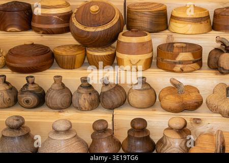 Collezione di contenitori in legno fatti a mano, ciotole e oggetti decorativi disposti su scaffali in legno in un mercato artigianale all'aperto. Foto Stock