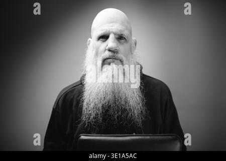 Foto in studio di un uomo calvo maturo con una lunga barba grigia su sfondo bianco e nero Foto Stock