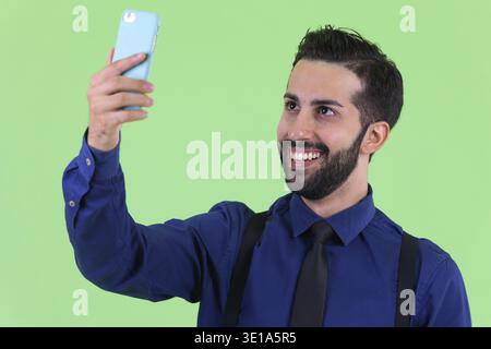 Foto in studio di un giovane e bellissimo uomo d'affari persiano barbato su sfondo verde Foto Stock