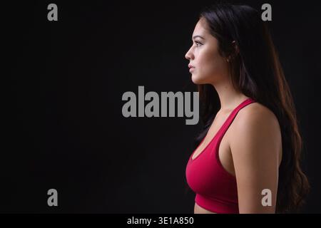 Foto in studio di una giovane bellissima donna multietnica pronta per la palestra su sfondo nero Foto Stock