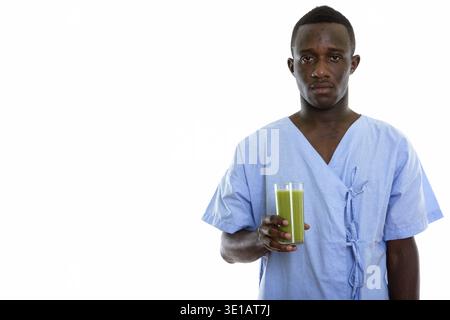 Studio shot del giovane africano nero uomo paziente tenendo un bicchiere di verde frullato vegetale Foto Stock