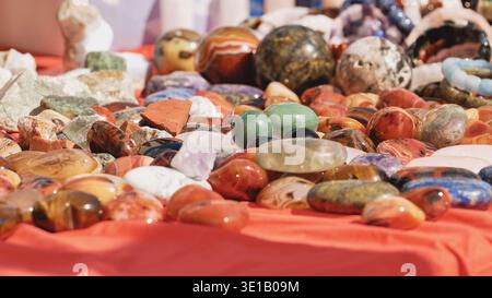Pietre preziose colorate lucidate e minerali adagiati su un panno rosso Foto Stock