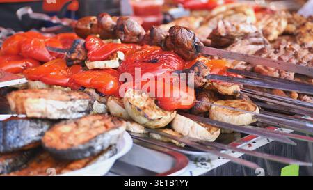Venditrice di cibo di strada che prepara verdure alla griglia e spiedini di carne Foto Stock