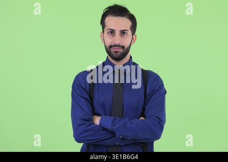 Foto in studio di un giovane e bellissimo uomo d'affari persiano barbato su sfondo verde Foto Stock