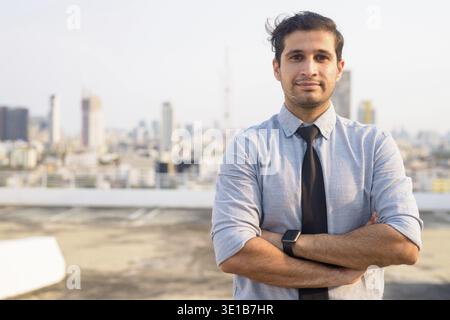 Ritratto di un giovane affascinante uomo d'affari iraniano contro la vista della città Foto Stock