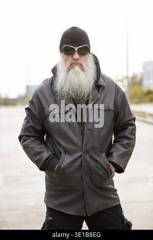 Ritratto di un uomo hipster maturo e affascinante con la barba lunga come motociclista in strada all'aperto Foto Stock