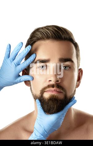 Bell'uomo durante il check-up prima di un intervento di plastica su sfondo bianco Foto Stock