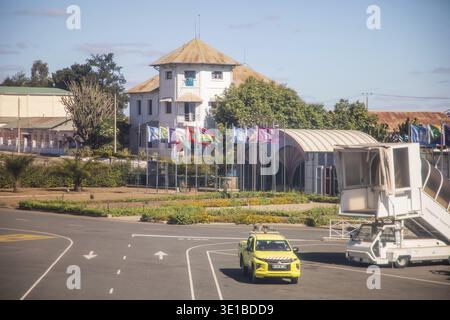 Antananarivo, Madagascar - 5 ottobre 2023: Terminal aeroportuale con bandiere e taxi gialli in un paesaggio luminoso e soleggiato Foto Stock