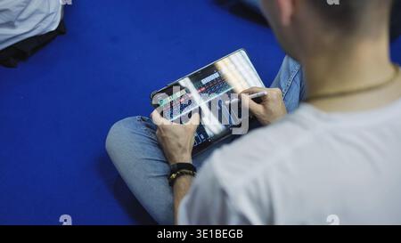 Persona che mescola l'audio su un tablet utilizzando uno stilo e si occupa di ingegneria audio da remoto Foto Stock