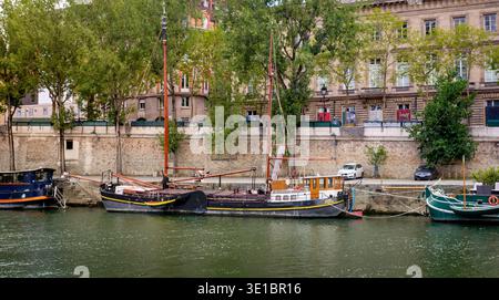 Parigi, Francia - 08 04 2025: Una classica vista di una tradizionale barca a vela in legno e chiatta ormeggiata lungo la banchina di pietra della Senna con parigina Foto Stock