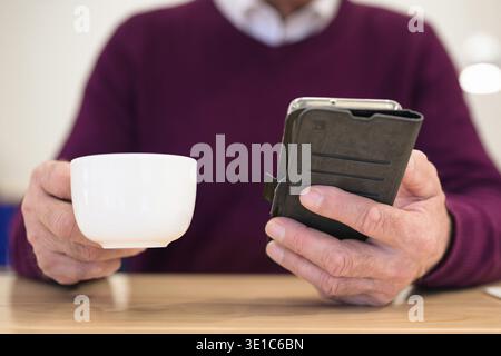 Primo piano di un uomo che usa uno smartphone durante la pausa caffè Foto Stock