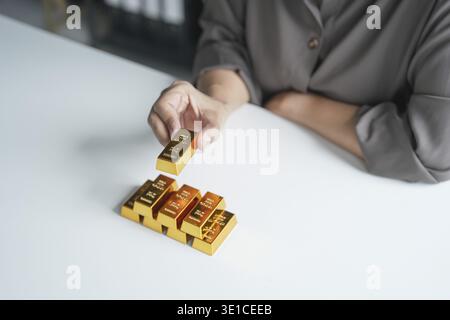 Anziana donna asiatica anziana che commercializza investimenti in risparmio d'oro per il reddito pensionistico e il profitto Golden Futures. donna d'affari degli anni '60 Foto Stock